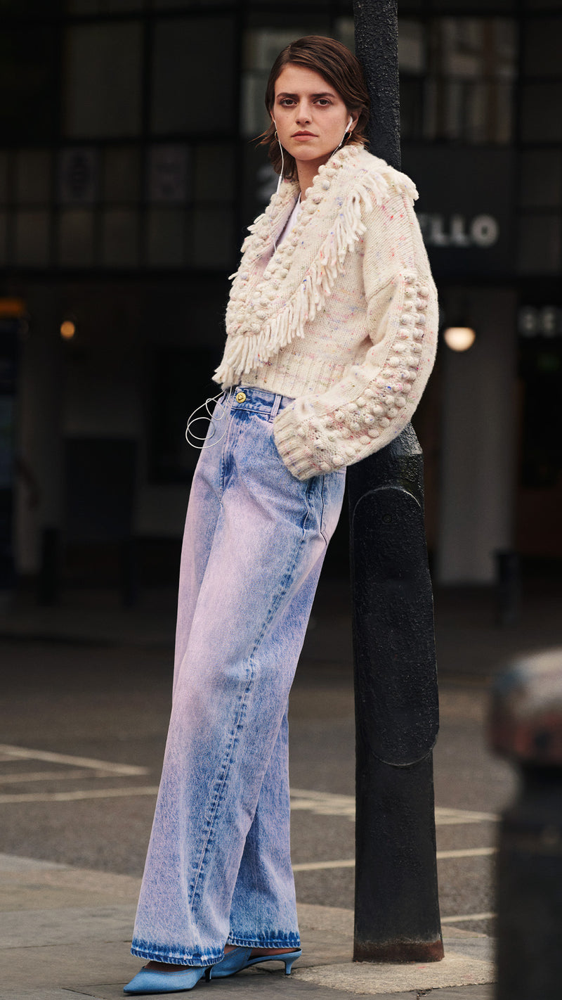model wears fluffy clouds alpaca bomber cardigan and acid washed wide leg jeans in portobello road