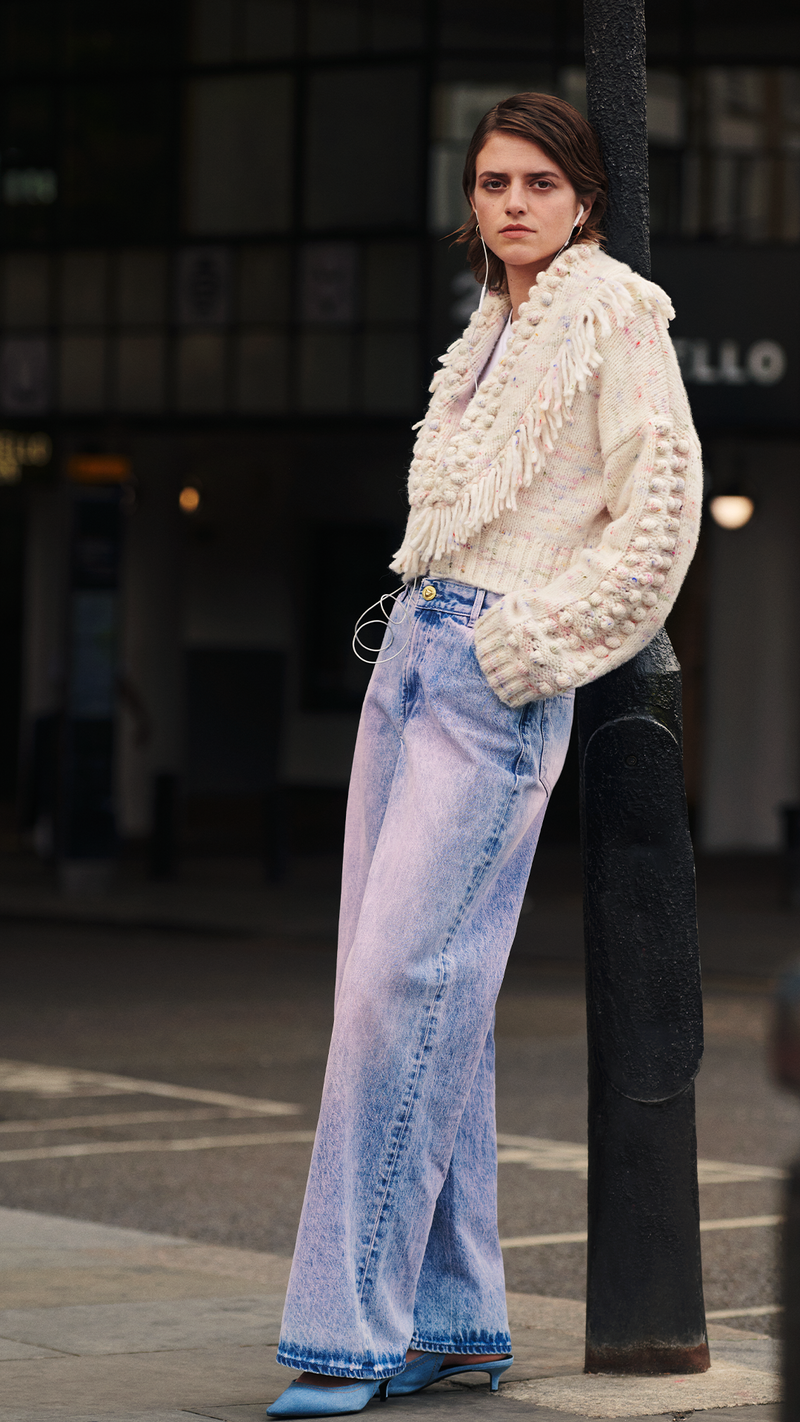 model wears fluffy clouds alpaca bomber cardigan and acid washed wide leg jeans in portobello road